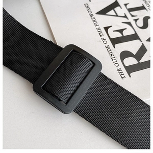 Detalle de la correa de nailon negro con hebilla de plástico mate en un bolso de lona