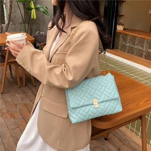 Quilted light blue chain shoulder bag with gold hardware in an elegant outdoor setting