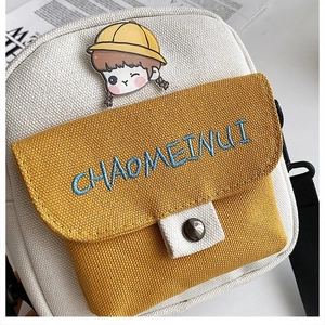 Detalle del bolso bandolera de lona con bordado CHAOMEINUI y broche de niña de dibujos