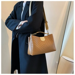 Detail of brown chevron quilted crossbody bag with wide strap on a model shoulder