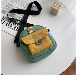 Detalle del bolso bandolera de lona verde con bolsillo amarillo y correa con logo