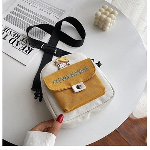 Primer plano de mini bolso bandolera de lona con bolsillo amarillo y pin de personaje lindo
