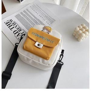 Detalle del bolso bandolera de lona con bolsillo amarillo y bordado de dibujos
