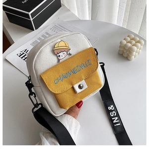 Detalle de mini bolso bandolera de lona con bolsillo amarillo, broche y correa con letras
