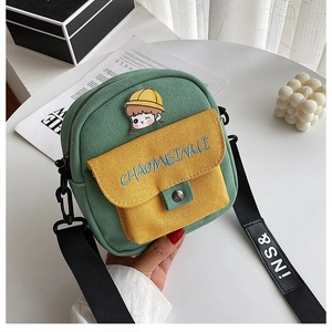 Detalle del bolso bandolera de lona verde con bordado y solapa amarilla en contraste