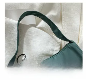 Detail of dark green fabric handbag featuring smooth metal zipper and comfortable handle