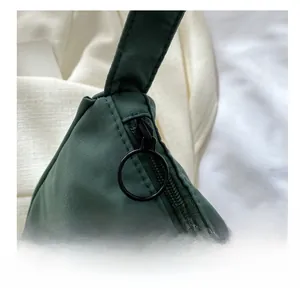 Detail of smooth metal zipper with black circular puller on dark green nylon bag
