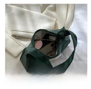 Interior view of the dark green crescent bag showing storage space for phone and makeup