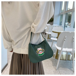 Detail of vintage green baguette bag with colorful cartoon embroidery in a cafe setting