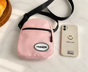 Mini bolso bandolera de lona rosa comparado con el tamaño de un smartphone