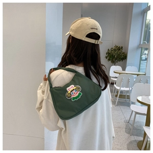 Detail of dark green canvas shoulder bag with colorful cartoon character embroidery