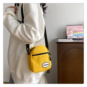 Detalle de un mini bolso bandolera de lona amarillo brillante con correa ajustable