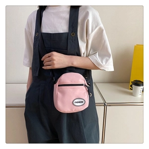 Detalle del bolso bandolera de lona rosa con correa ajustable y parche de moda