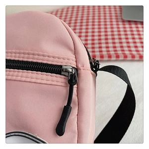 Detalle de cremallera negra y tirador metálico en bolso de lona de nailon rosa