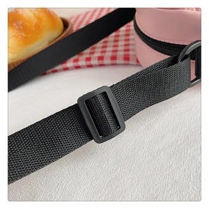 Detalle de la correa ajustable negra y la hebilla en el bolso rosa