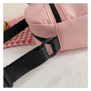 Detalle del bolso de lona rosa con cremallera negra y costuras de la correa de hombro