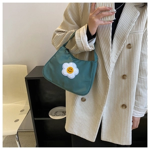 Detail of dark green shoulder bag featuring a white sunflower smiley face patch embroidery