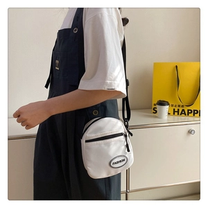 Bolso bandolera de lona blanca con correa ajustable negra y etiqueta en la modelo
