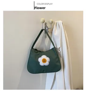Detail of dark green nylon baguette bag with embroidered smiling flower and black zipper