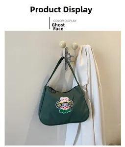 Close-up of deep green underarm bag with colorful cartoon face embroidery and zipper