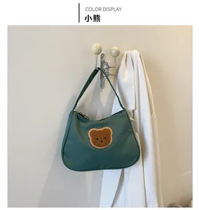 Close-up of green canvas baguette bag with brown plush teddy bear patch embroidery detail