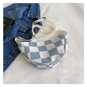 Detail of light blue checkered crescent bag with adjustable knit shoulder strap