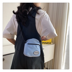 Bolso bandolera pequeño de lona azul claro con correa negra en modelo informal
