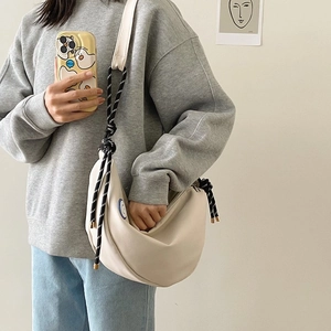 Détail du sac croissant en toile beige avec bandoulière en corde et patch smiley