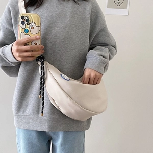 Sac bandoulière demi-lune minimaliste en toile beige avec écusson smiley et sangle tressée