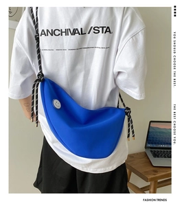 Détail du sac croissant bleu avec badge smiley et bandoulière en corde tressée