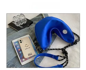 Détail du sac demi-lune bleu Klein en nylon avec motif smiley et bandoulière tressée