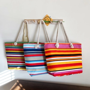 Detail of colorful striped canvas tote bags with white cotton rope handles hanging on hooks