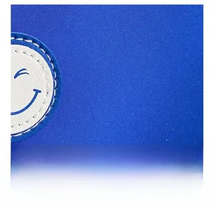 Détail du tissu en toile sergé bleu avec un patch en cuir blanc à motif smiley souriant