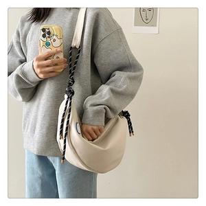 Détail du sac croissant en toile crème avec bandoulière en corde nouée et écusson sourire