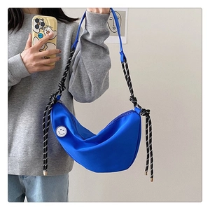 Sac croissant en nylon bleu avec badge smiley et bandoulière tressée sur modèle