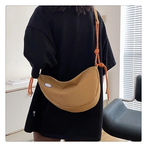 Détail du sac demi-lune en toile kaki avec bandoulière tressée et patch sourire