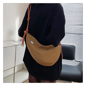 Détail du sac demi-lune en toile kaki avec bandoulière tressée et patch logo
