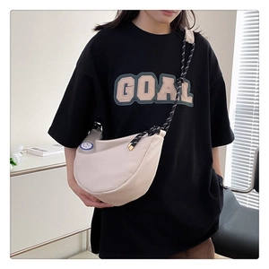 Détail du sac bandoulière en toile crème avec sangle tissée noire et patch smiley