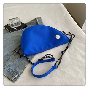 Détail du sac bandoulière en nylon bleu avec sangle tressée et logo smiley blanc