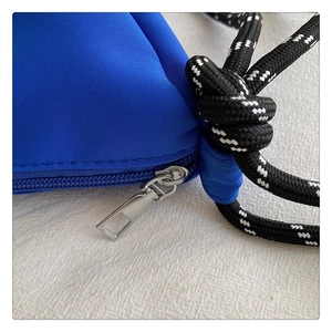 Détail de la fermeture éclair en métal argenté et de la corde tressée sur le sac bleu