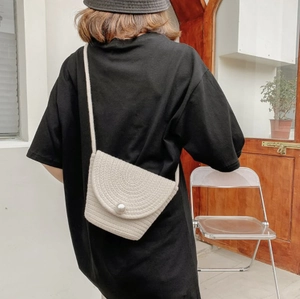 Detail of beige woven rope bucket bag featuring a large pearl clasp and spiral texture