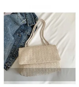 Nahaufnahme der cremefarbenen Strohtasche mit Fischgrätenmuster und Klappverschluss-Detail