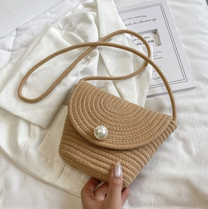 Close-up of woven cotton rope crossbody bucket bag with pearl accent and fine strap