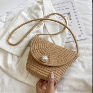 Detail of hand-woven cotton rope bucket bag with a large pearl accent and flap closure