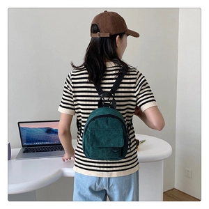 Vue arrière d'une femme portant le mini sac à dos en velours côtelé vert foncé au bureau