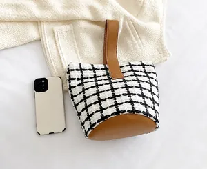 Top view of mini black and white plaid tweed bucket bag with brown leather base and handles