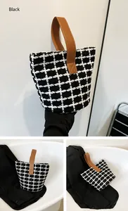 Detailed view of black and white plaid tweed bucket bag with brown leather handles