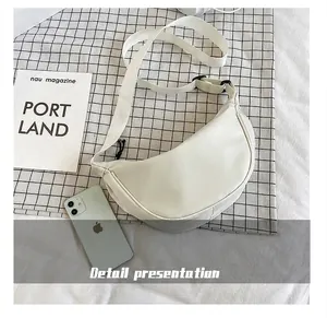 Bolso bandolera de nylon blanco con correa ajustable mostrado junto a un smartphone