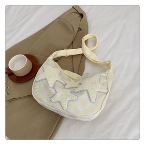 Détail du sac bandoulière beige à motifs losanges et écussons étoiles en peluche