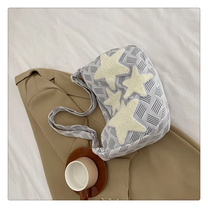 Détail du sac bandoulière en tricot rayé avec de grandes étoiles en peluche blanches